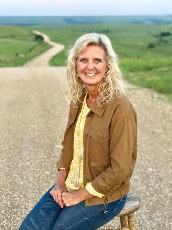 Woman in brown jacket on a dirt road.