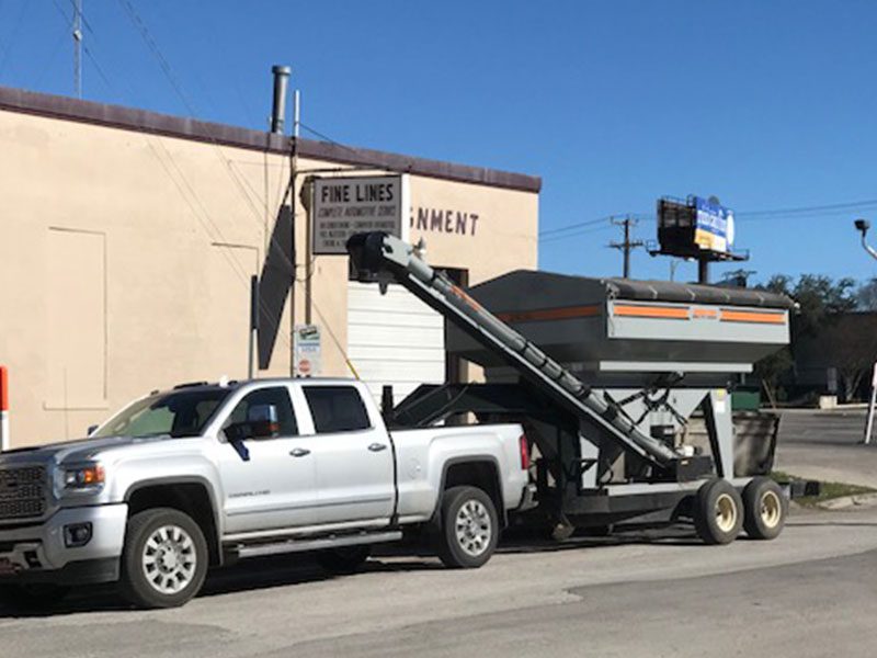 White pickup truck hauling a grain bin.