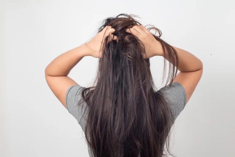 Woman with long hair scratching her head.