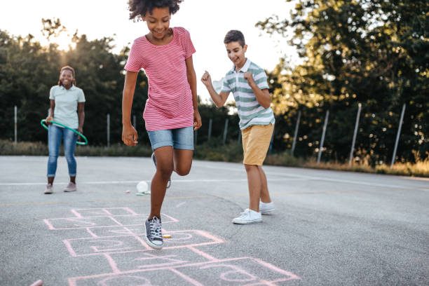 Three kids playing hopscotch outdoors.