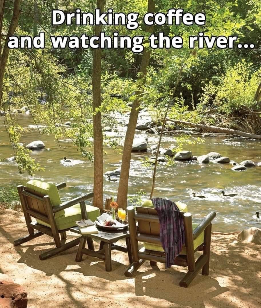 Two chairs by a river with coffee.