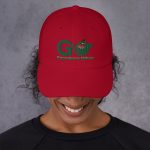 Person wearing red cap with nature logo.