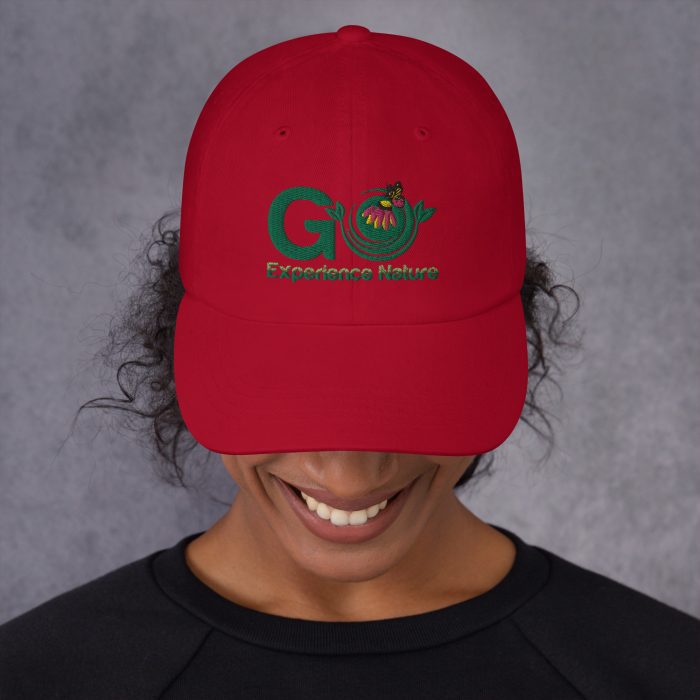 Person wearing red cap with nature logo.