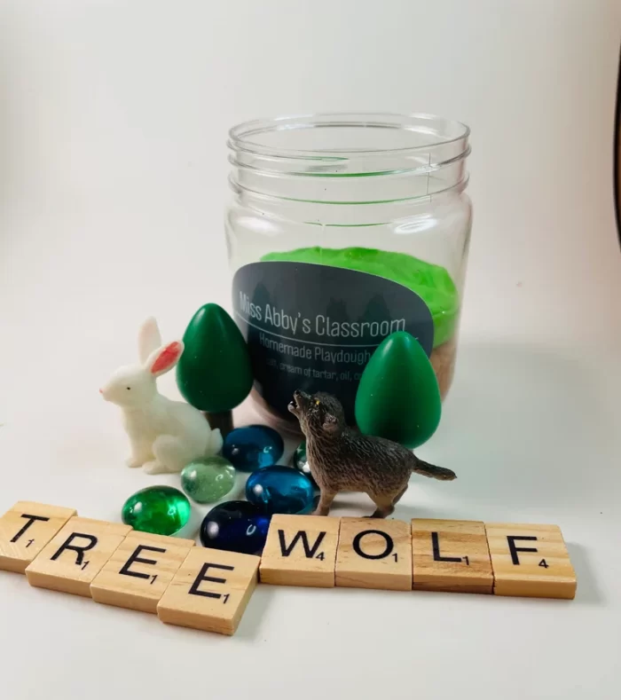 Playdough scene with tree, wolf, and rabbit.