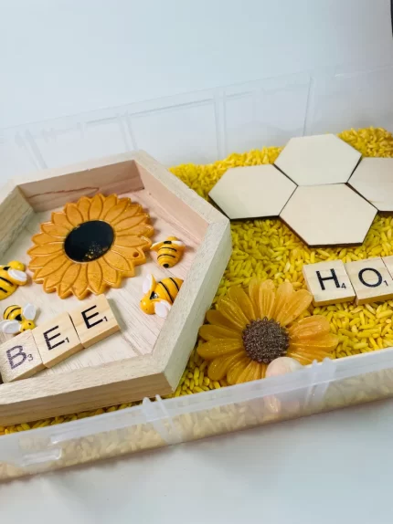 Bee-themed sensory bin with sunflowers and honeycomb.