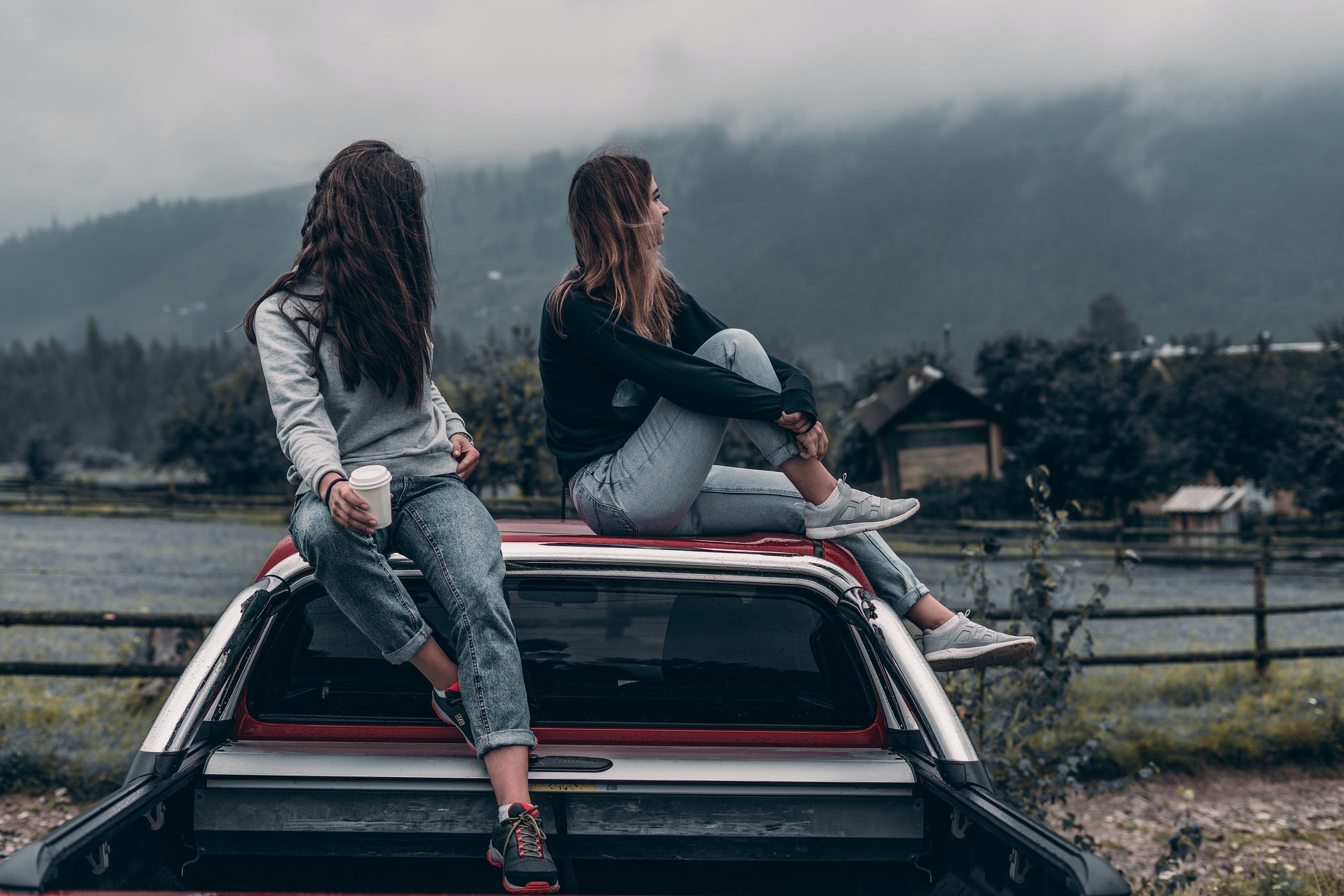 Two women sitting on truck bed.