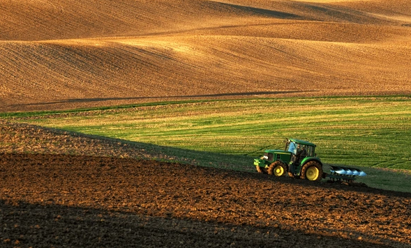 Tractor plowing a field with rolling hills.