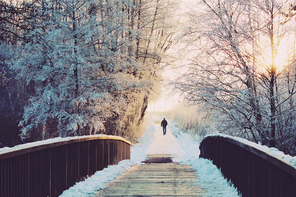 Snowy path with bridge and lone figure.